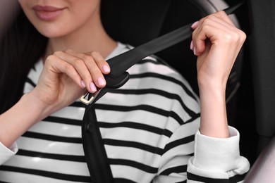 Woman fastening safety seat belt inside modern car