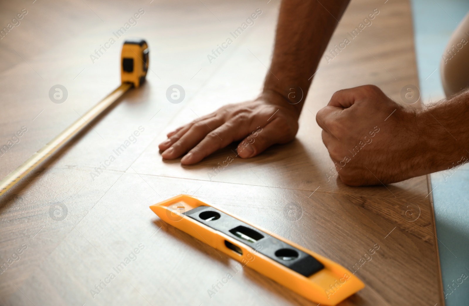 Photo of Professional worker installing new parquet flooring indoors, closeup