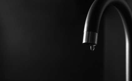 Photo of Closeup view of water dropping from faucet indoors. Space for text