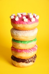 Photo of Stacked sweet tasty glazed donuts on yellow background