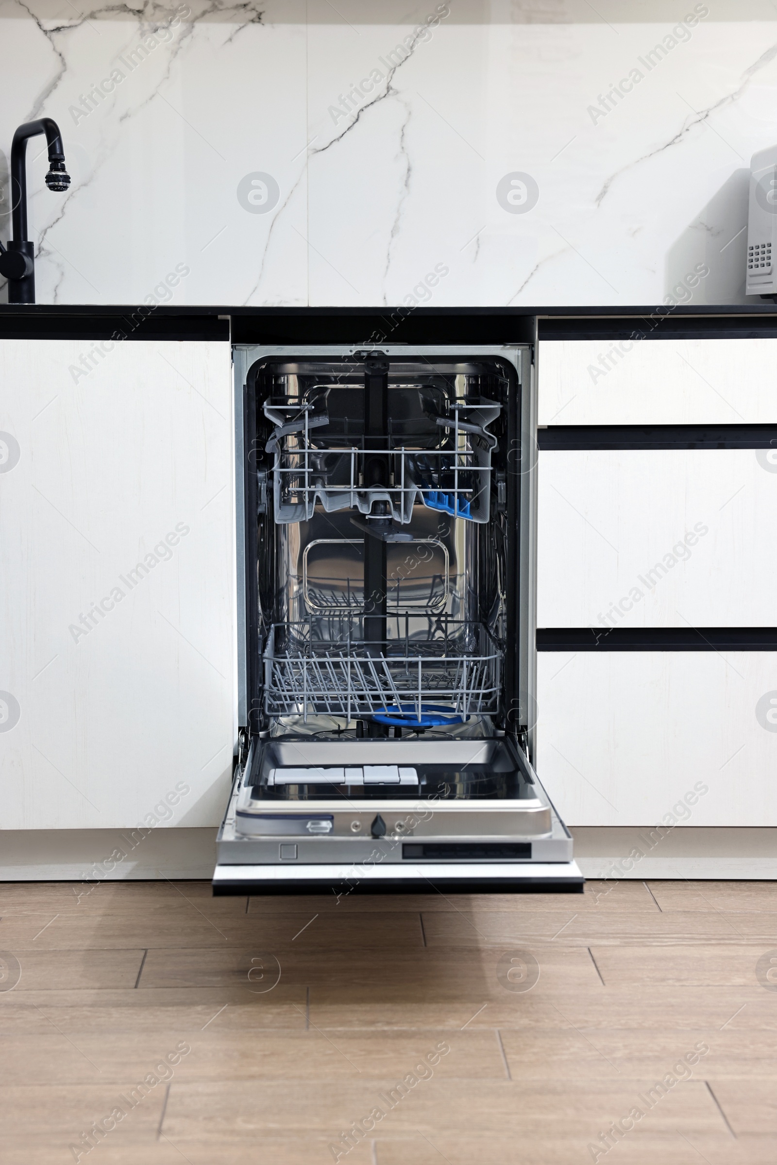 Photo of Open clean empty dishwasher in kitchen. Home appliance