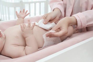 Photo of Mother changing baby's diaper on table at home, closeup