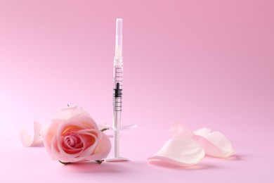 Photo of Cosmetology. Medical syringe, rose flower and petals on pink background, space for text