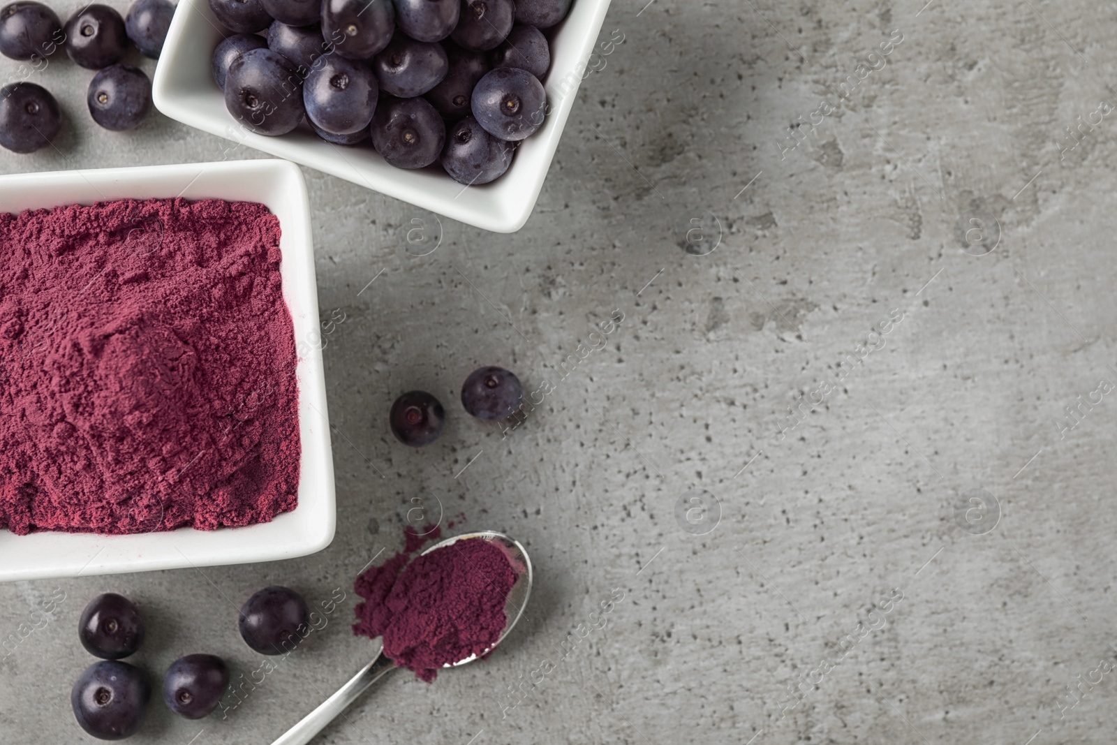 Photo of Acai powder and berries on grey background, flat lay. Space for text