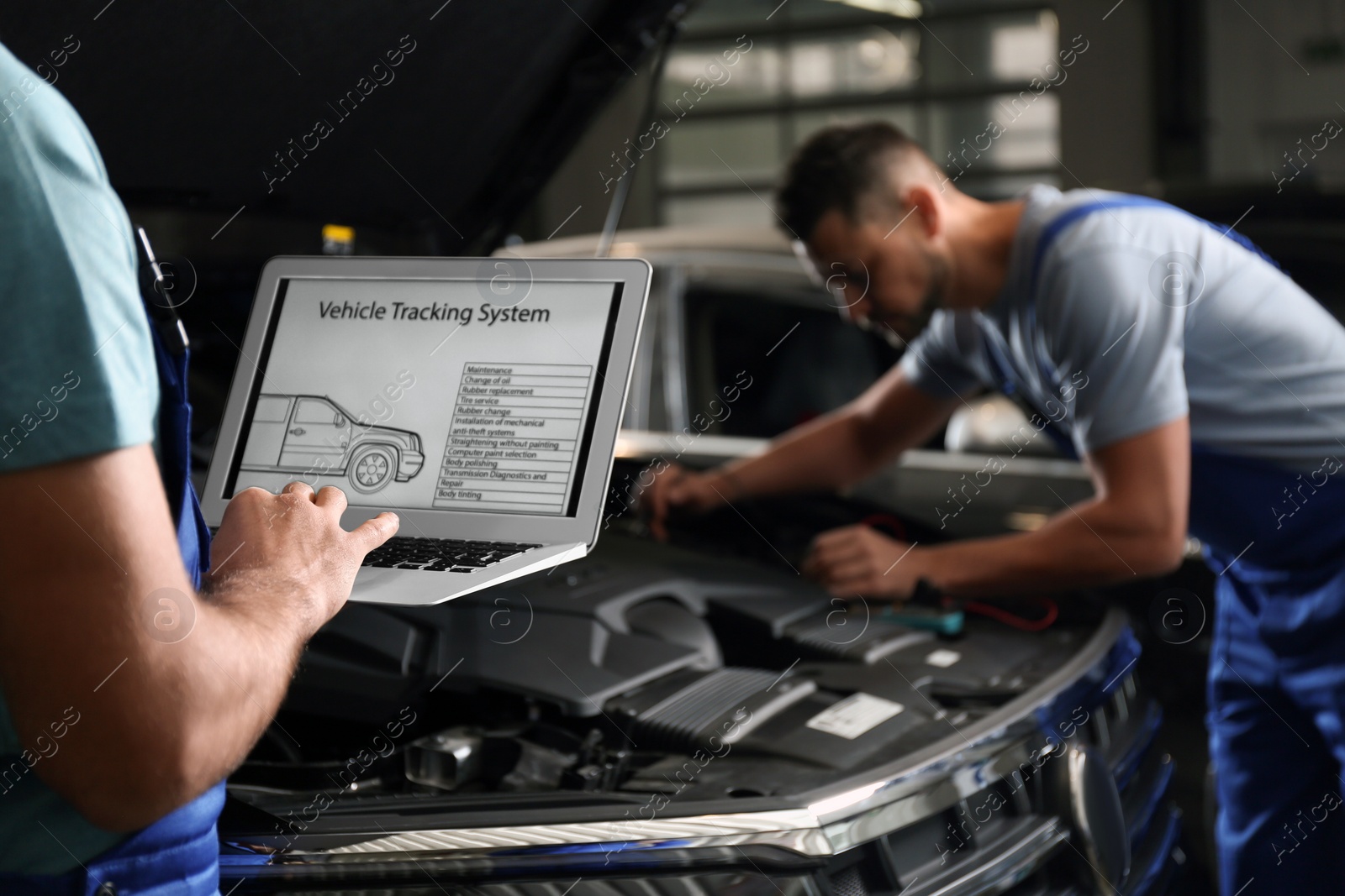 Photo of Mechanic with laptop doing car diagnostic at automobile repair shop, closeup