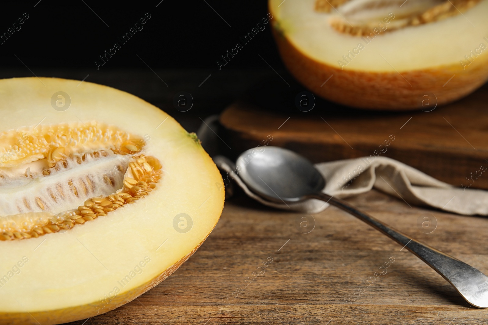 Photo of Half of tasty ripe melon on wooden table, closeup