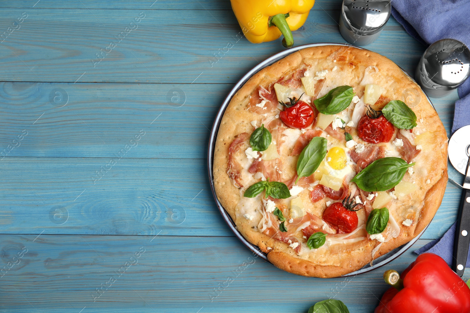 Photo of Delicious homemade pita pizza and ingredients on light blue wooden table, flat lay. Space for text