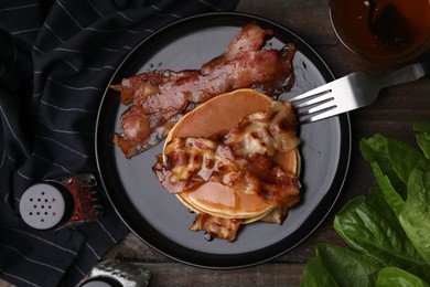 Delicious pancakes with fried bacon served on wooden table, flat lay