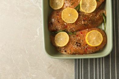 Photo of Chicken breasts with lemon and rosemary on grey table, top view