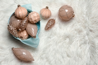 Collection of beautiful Christmas tree baubles on white faux fur, flat lay. Space for text