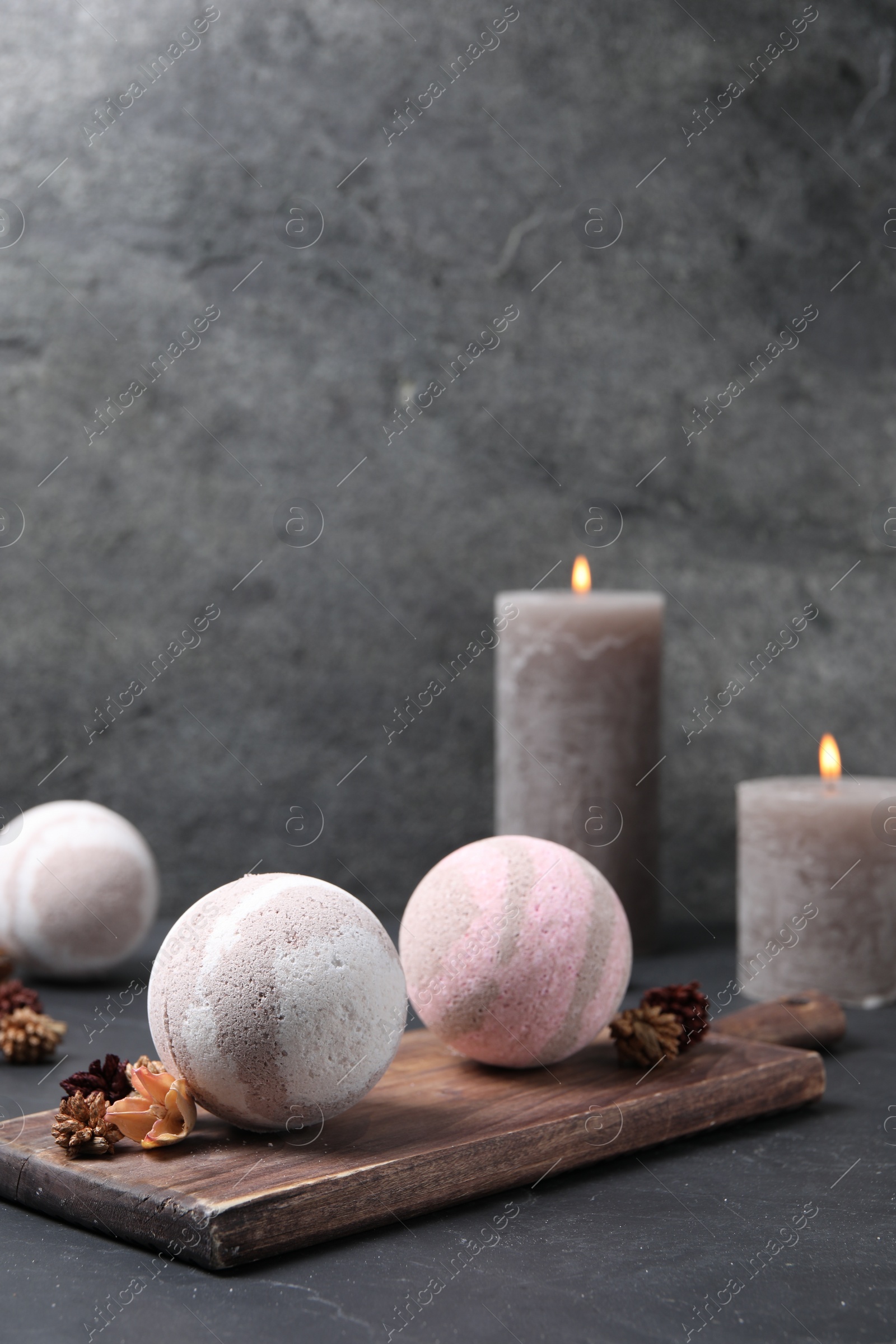 Photo of Bath bombs, dry flowers and burning candles on black table