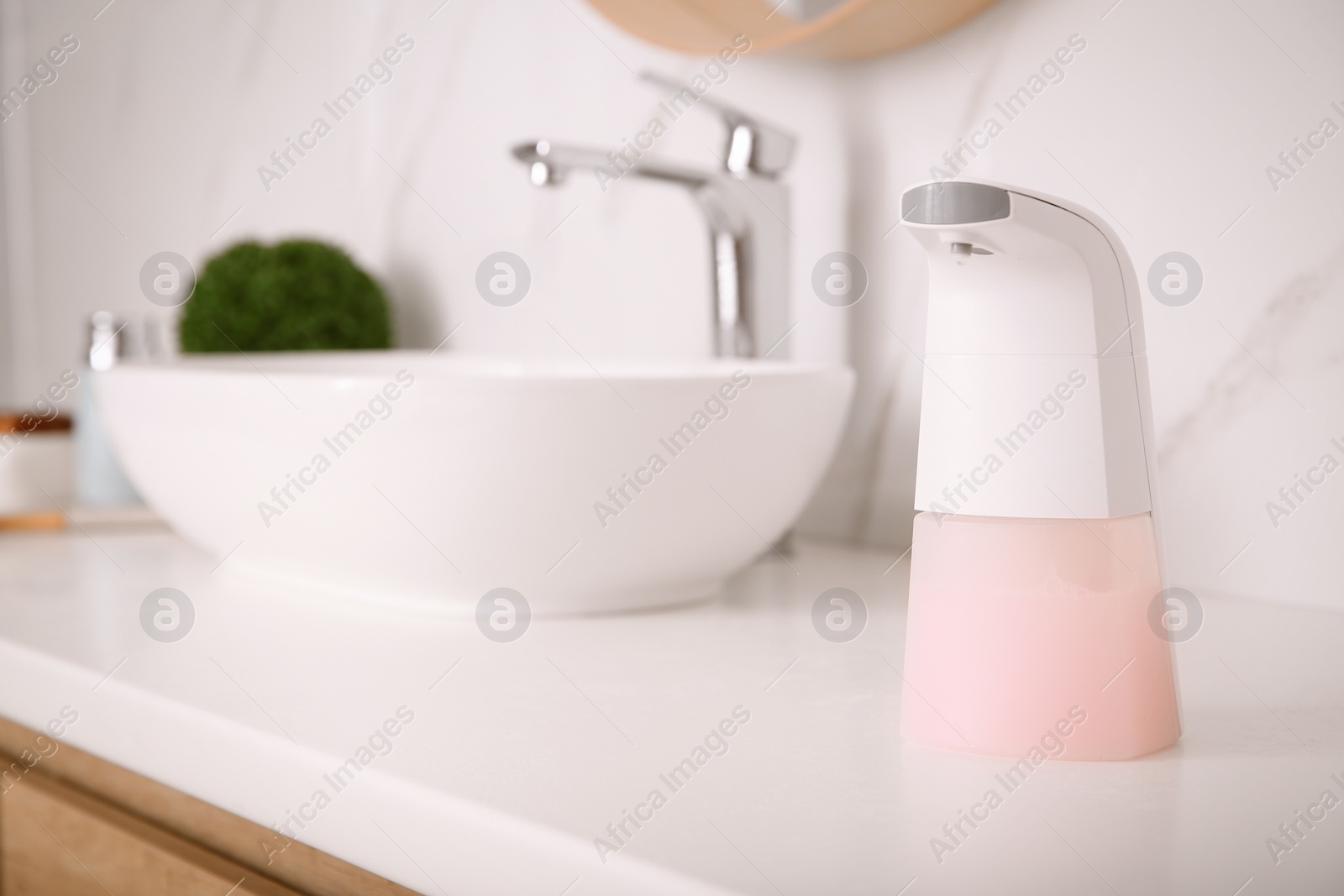 Photo of Modern automatic soap dispenser on countertop in bathroom
