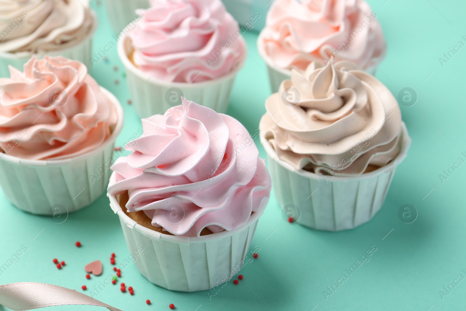 Photo of Delicious birthday cupcakes and sprinkles on turquoise background, closeup