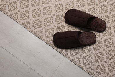 Photo of Brown slippers on carpet, space for text