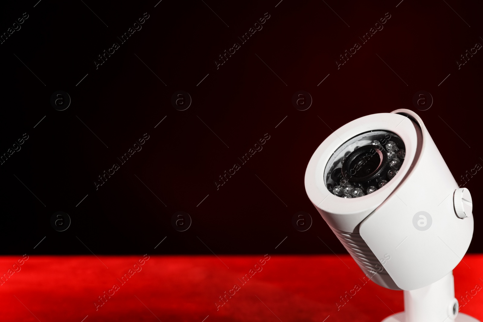 Photo of Modern security CCTV camera on table against dark background