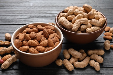 Photo of Bowls with organic nuts on wooden table. Snack mix