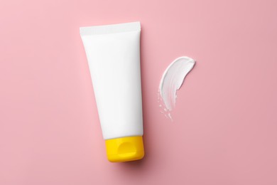 Photo of Tube of face cream and sample on pink background, top view