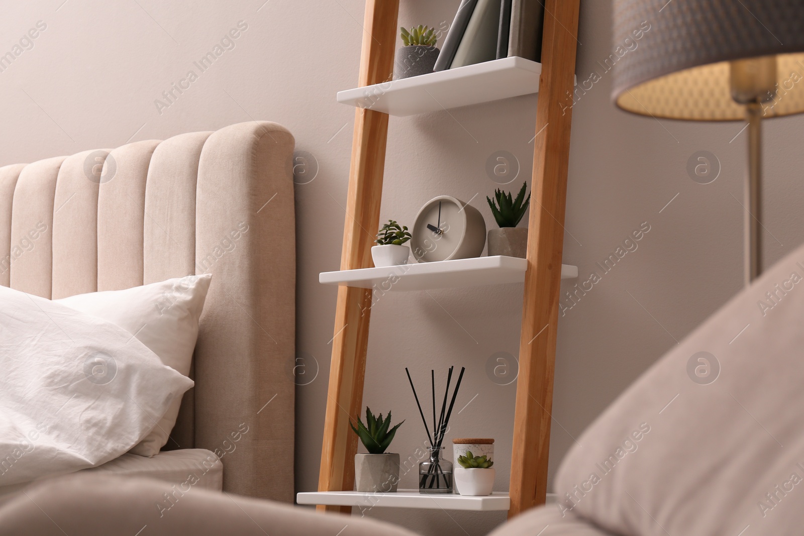 Photo of Stylish bedroom interior with decorative ladder and plants near grey wall