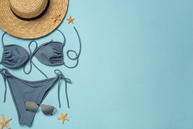 Photo of Stylish bikini, straw hat, sunglasses and starfishes on light blue background, flat lay. Space for text