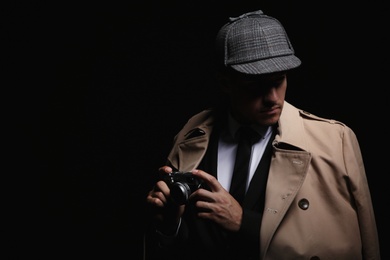 Photo of Old fashioned detective with camera on dark background. Space for text