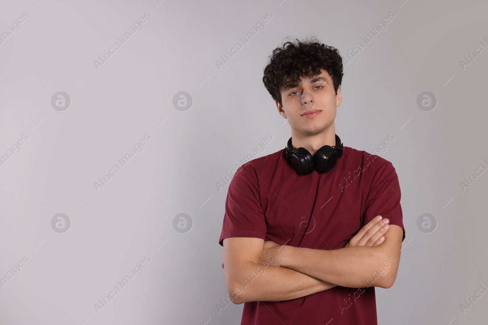 Photo of Portrait of handsome young man with headphones on light grey background. Space for text