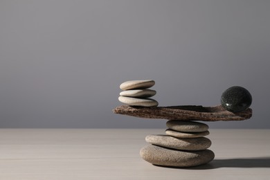 Photo of Stack of stones with tree branch on wooden table, space for text. Harmony and balance concept