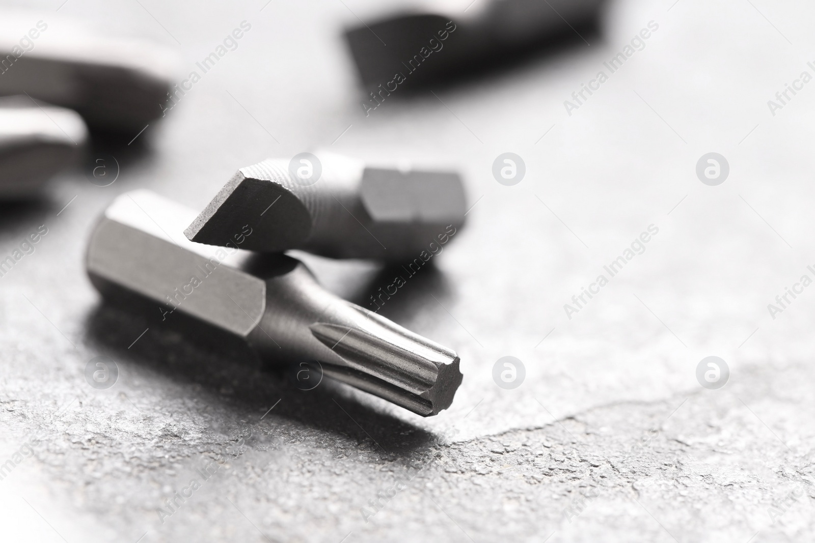 Photo of Different screwdriver bits on grey table, closeup. Space for text