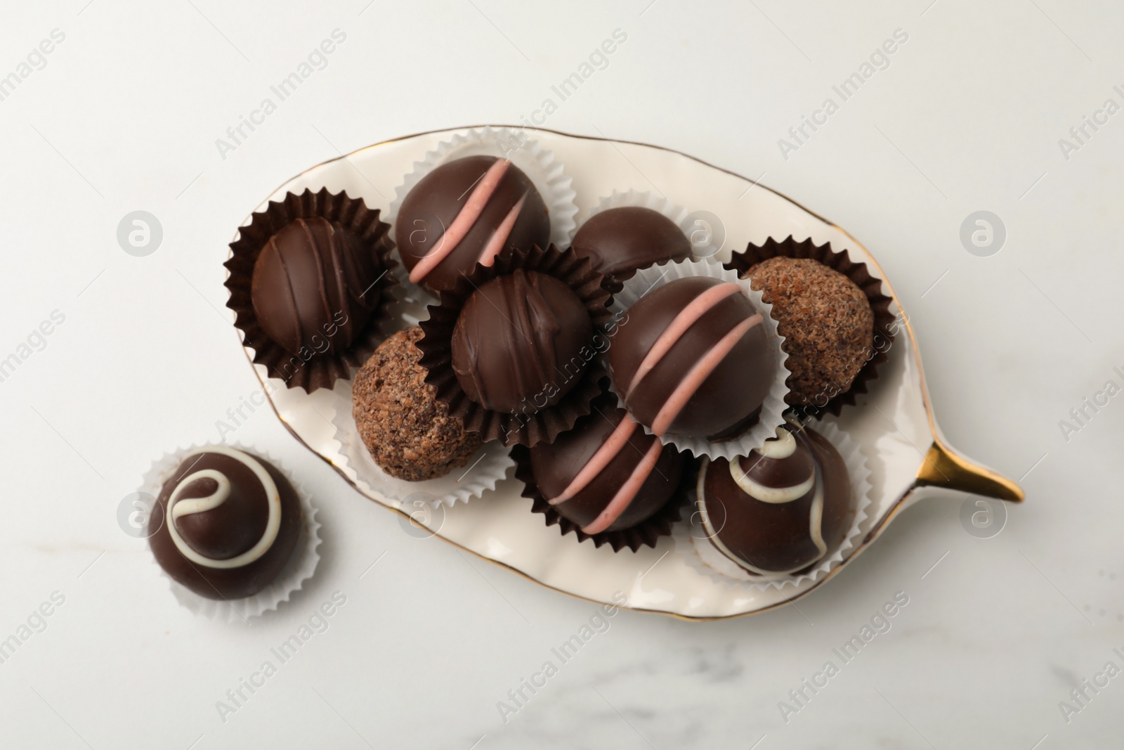 Photo of Different delicious chocolate truffles on white marble table, flat lay