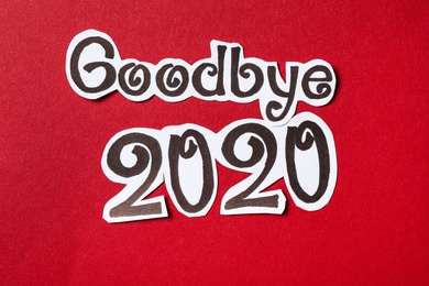 Photo of Phrase Goodbye 2020 cut out of paper on red background, flat lay