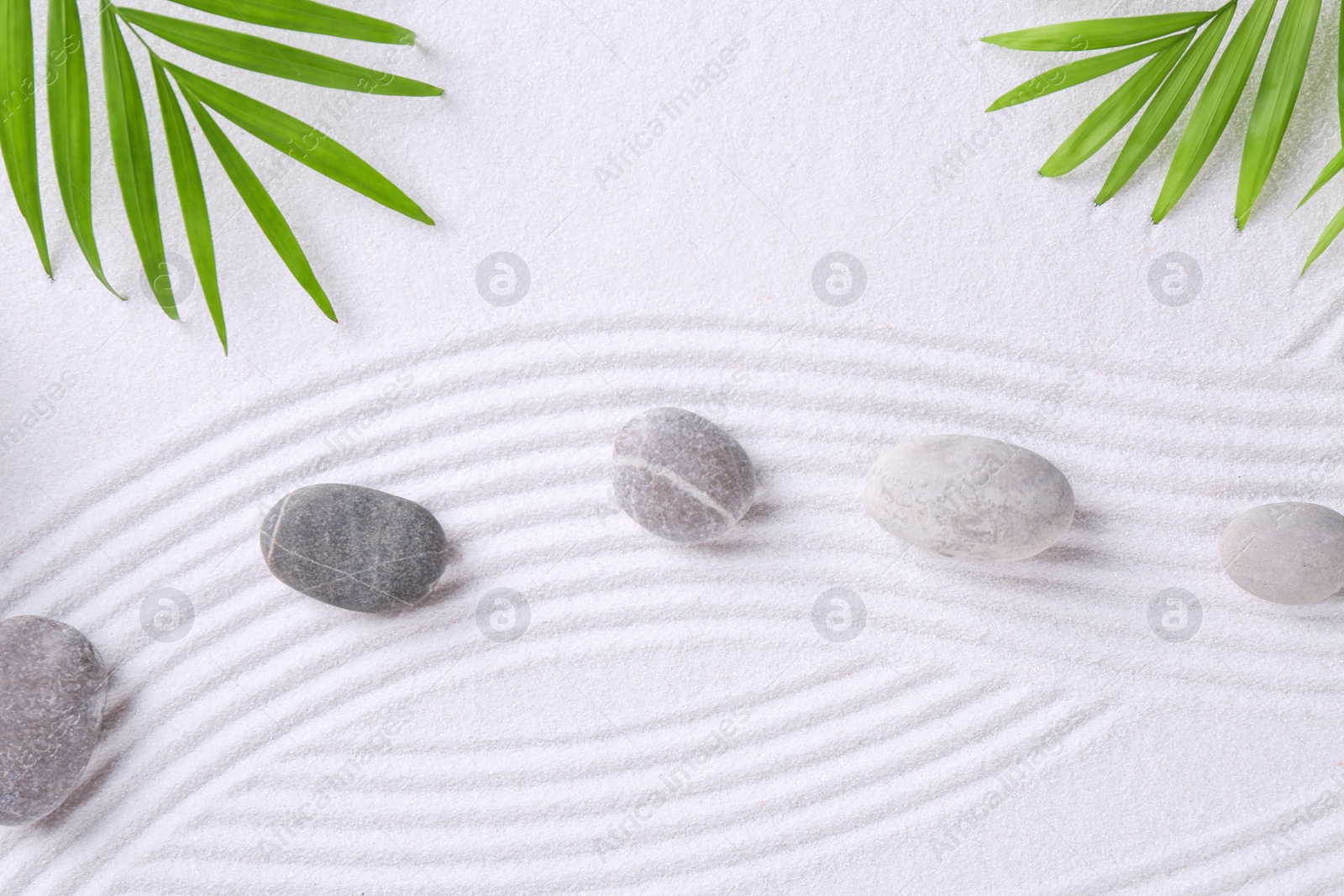 Photo of Zen garden stones and green leaves on white sand with pattern, flat lay