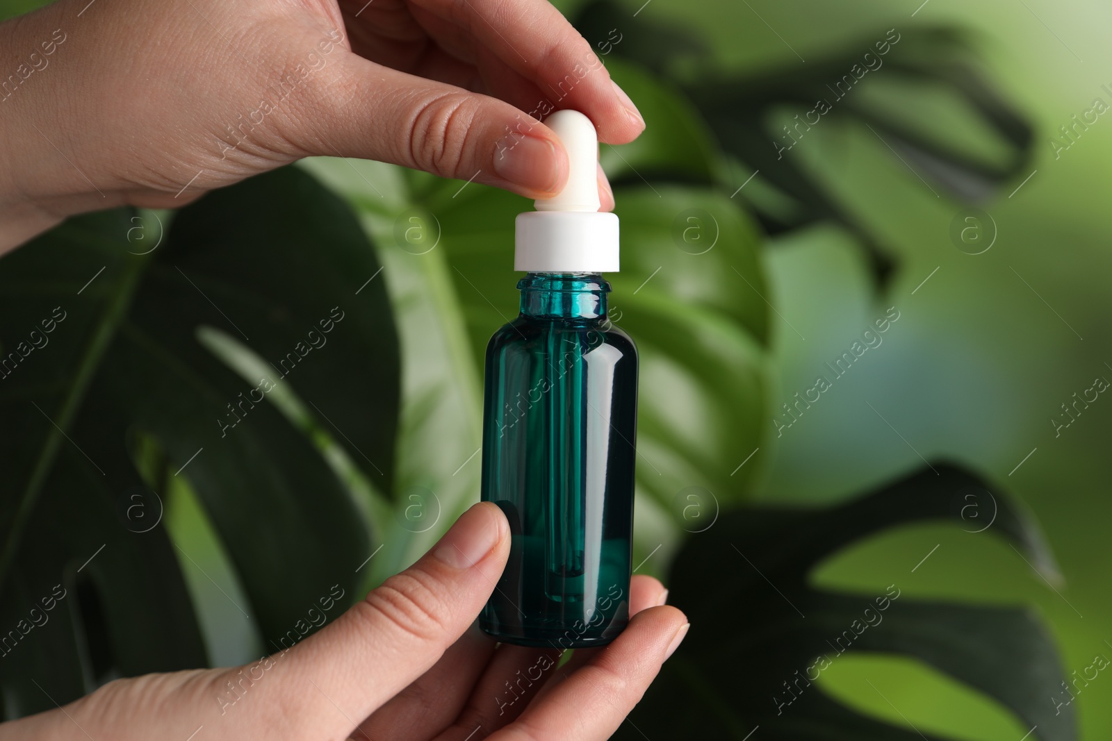 Photo of Woman with bottle of cosmetic serum on green background, closeup. Space for text