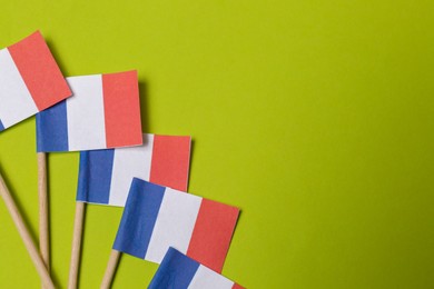 Photo of Small paper flags of France on green background, flat lay. Space for text