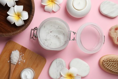 Photo of Body scrub, sea salt and plumeria flowers on pink background, flat lay