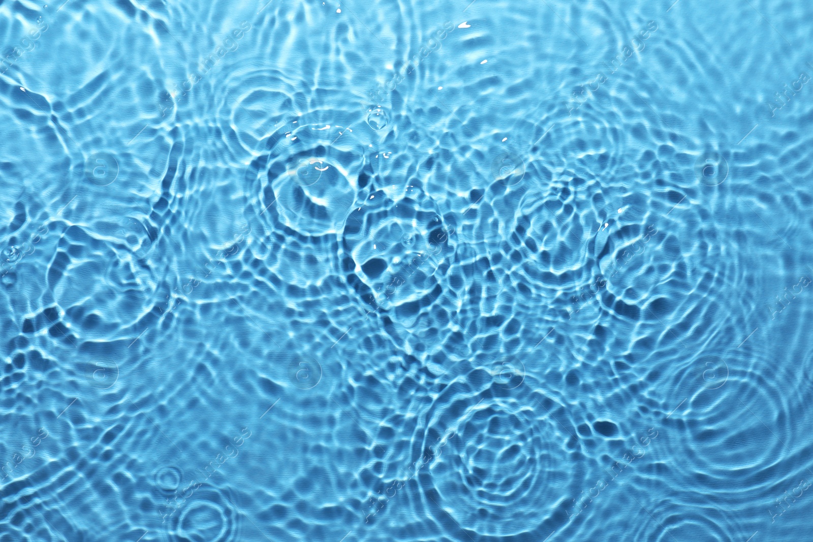 Image of Rippled surface of clear water on light blue background, top view