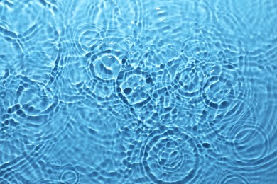 Rippled surface of clear water on light blue background, top view