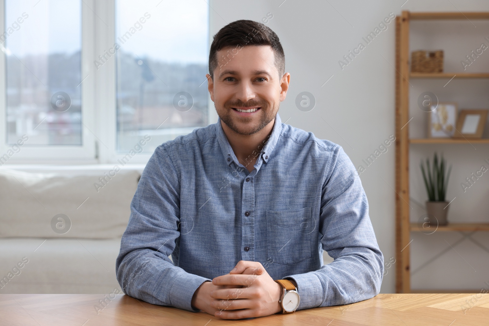 Photo of Happy man having video call at wooden table in room, view from web camera