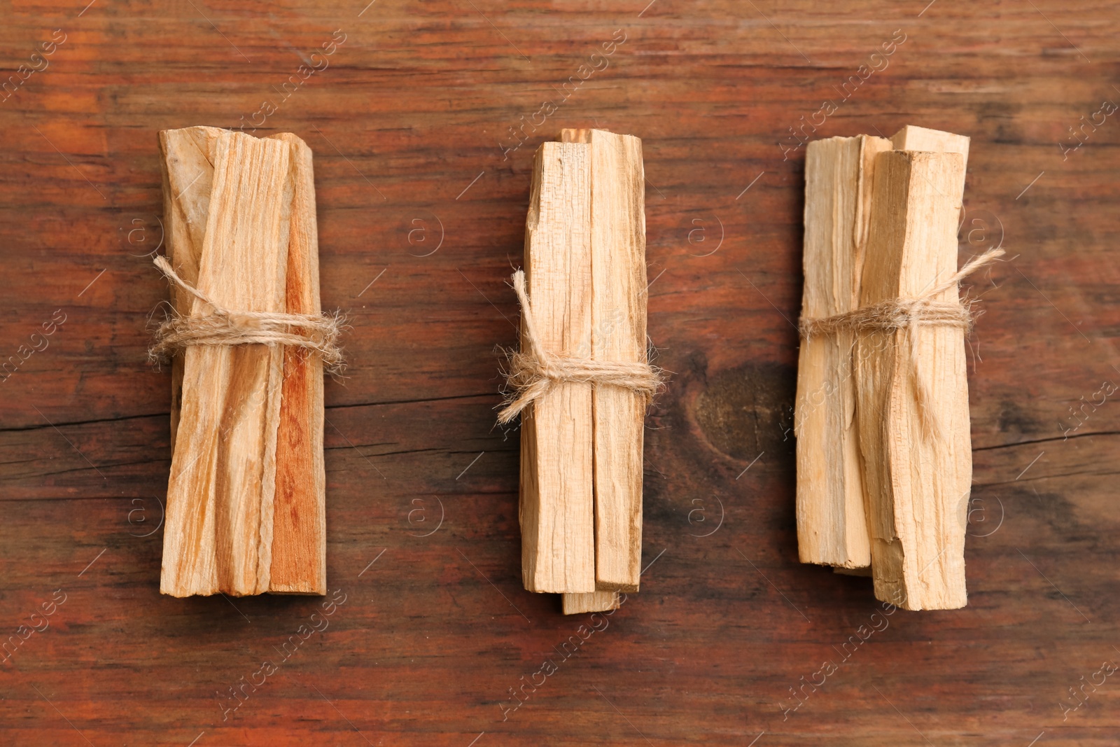 Photo of Bunches of tied Palo Santo sticks on wooden table, flat lay