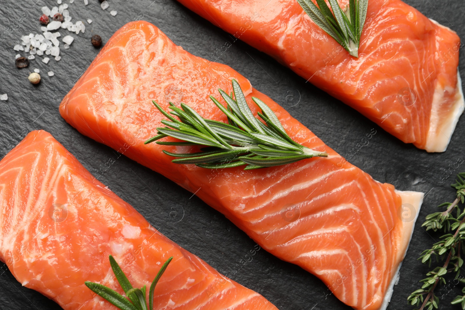 Photo of Fresh raw salmon and ingredients for marinade on black table, above view