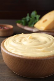 Photo of Tasty cheese sauce in bowl on wooden table, closeup