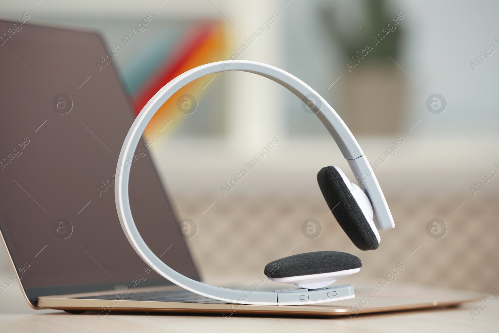 Photo of Modern headphones and laptop on table indoors