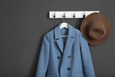 Coat and hat on wall hanger in stylish hallway interior