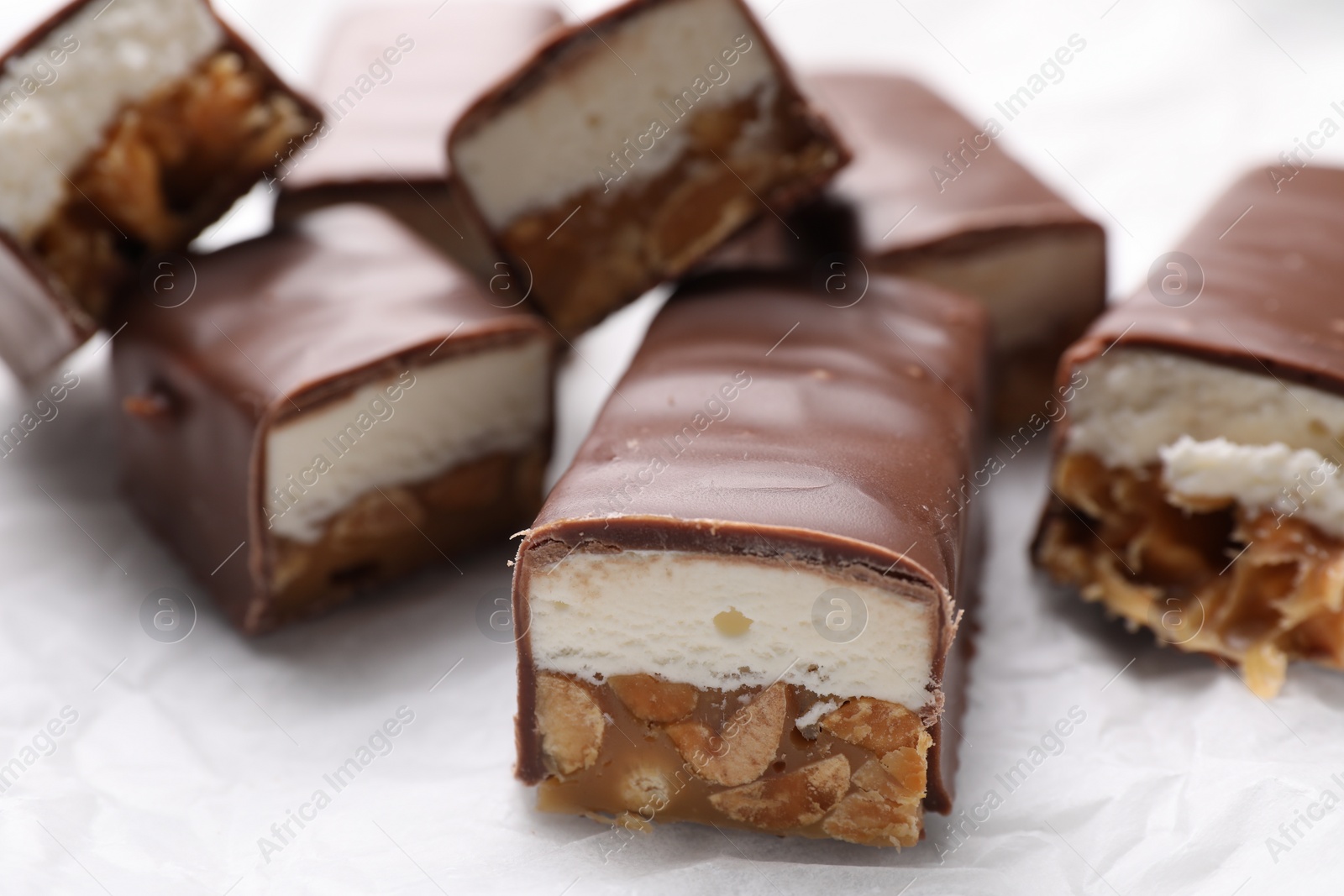 Photo of Tasty chocolate bars with nougat and nuts on white table, closeup