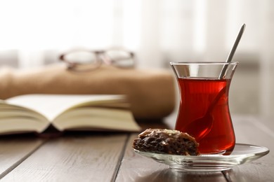 Photo of Glass of traditional Turkish tea and delicious baklava on wooden table, space for text