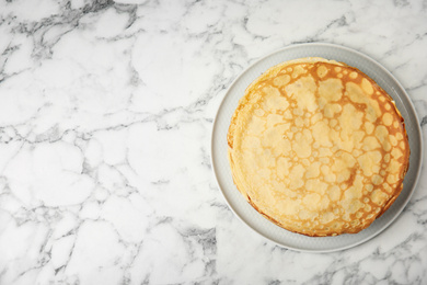 Photo of Stack of fresh thin pancakes on white marble table, top view. Space for text