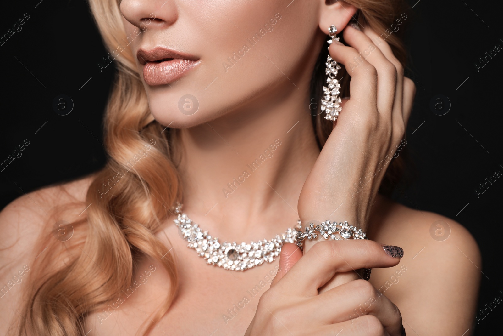 Photo of Beautiful young woman with elegant jewelry on dark background, closeup