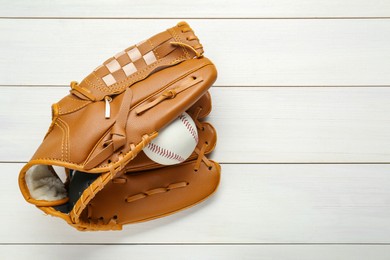 Photo of Leather baseball glove with ball on white wooden table, top view. Space for text