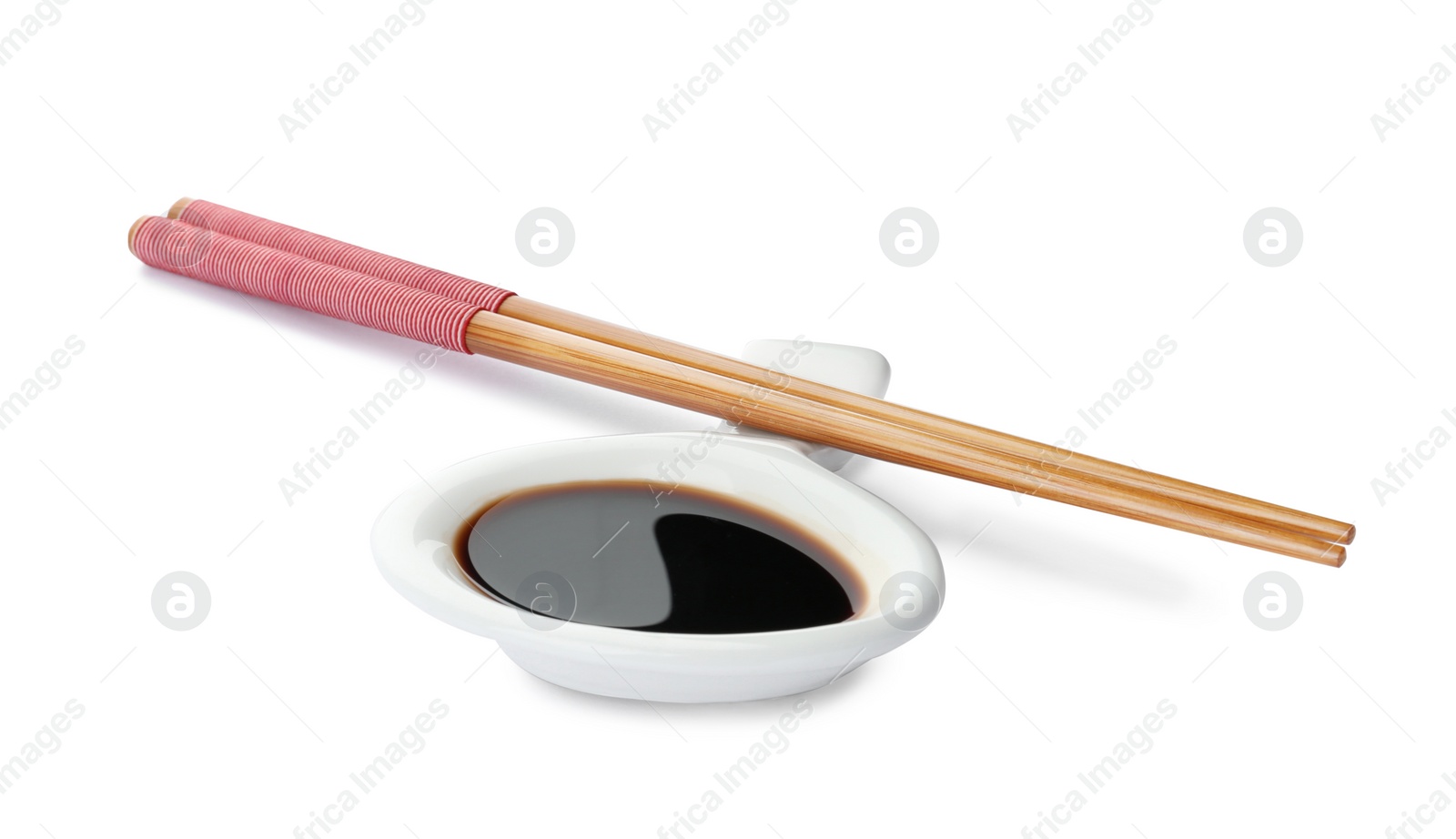 Photo of Dish of soy sauce with chopsticks on white background