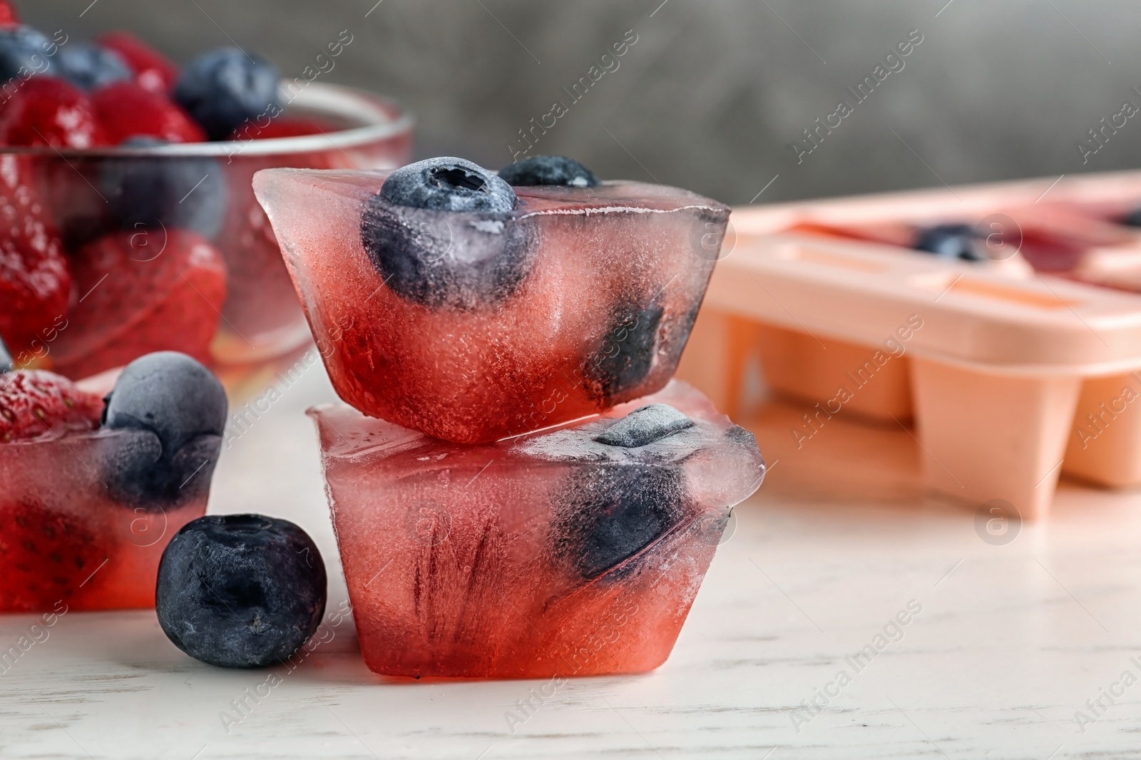 Photo of Ice cubes with berries on table, closeup