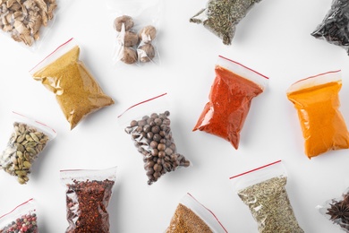 Photo of Plastic bags with different spices on white background, top view
