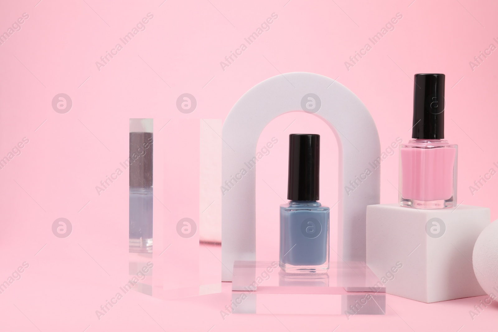 Photo of Stylish presentation of nail polishes on pink background